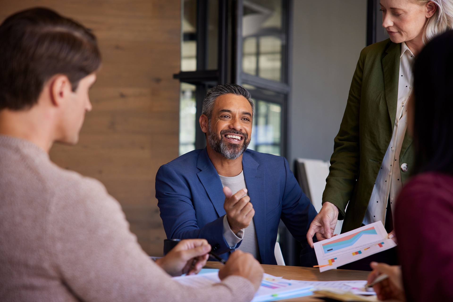 Happy businessman smiling while discussing sales with his team Happy businessman smiling while discussing sales with his team